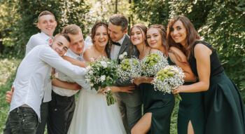 a wedding party hugging the bride and groom